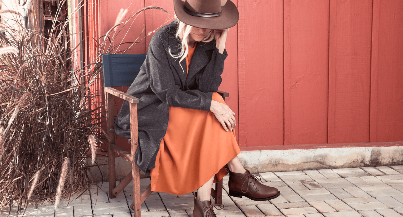 Mulher em ambiente rural usando chapéu, cinto country feminino com fivela e coturno